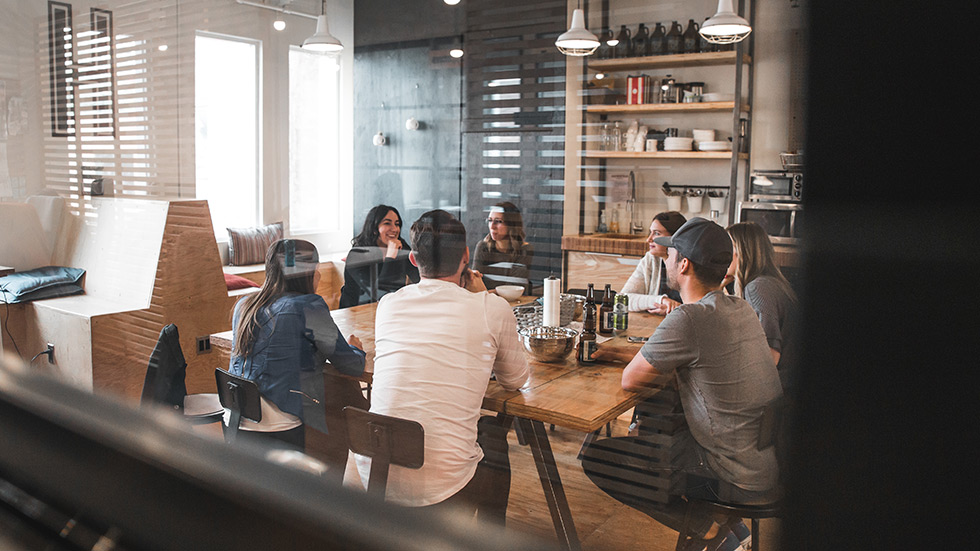 People in a room sitting and discussing around a table